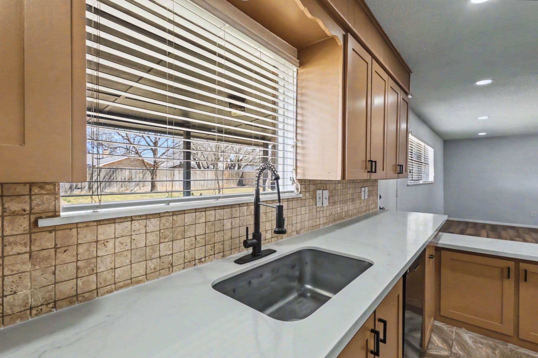 Updated kitchen in a Levelland, TX ranch listing with stainless appliances, tiled backsplash, and window light.